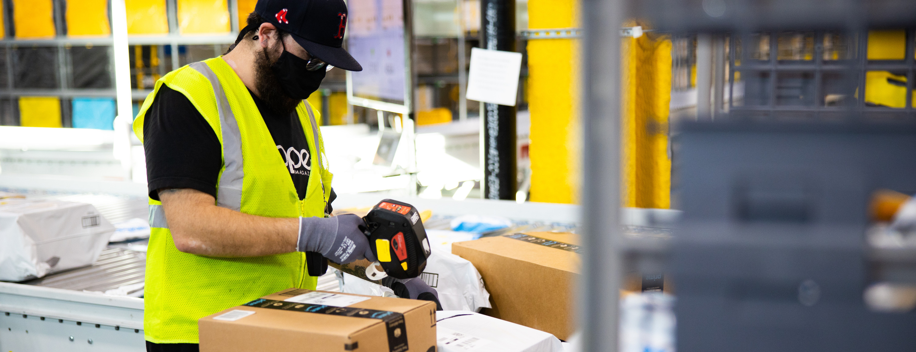 Amazon employee wrapping boxes on a conveyor belt